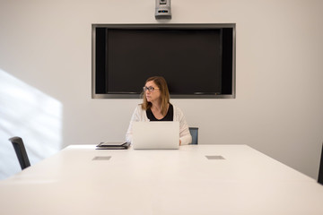 woman sitting alone in conference room preparing for meeting