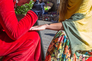Fototapeta premium A woman making temporary henna tattoo on woman's hand.