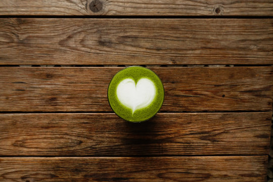 A cup of green tea matcha latte on wooden background