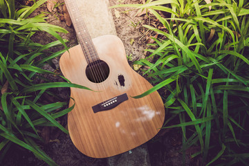 Old acoustic guitar with a broken hole in the garden.