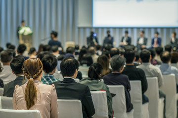 Rear view of Audience in the conference hall or seminar meeting which have Speakers on the stage, business and education about investment concept