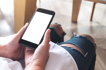 Mockup image of woman's hand holding black mobile phone with blank white desktop screen in cafe