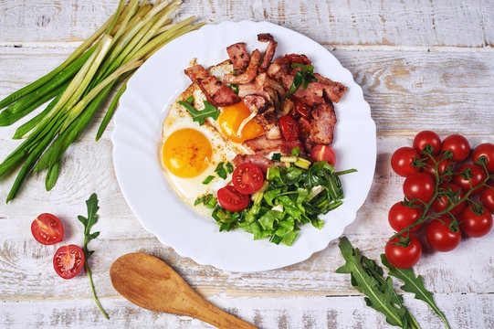 Fried eggs with bacon, tomatoes and greens. Light summer Breakfast