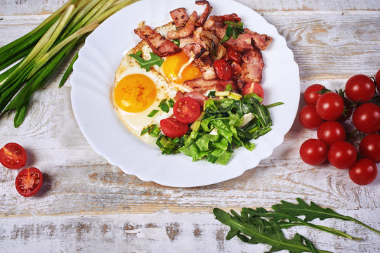 Fried eggs with bacon, tomatoes and greens. Light summer Breakfast