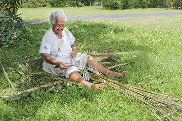Old aged Polynesian Cook Islander woman prepares a broom from a coconut tree leaves in Rarotonga  Cook Islands
