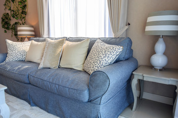 Beige pillows on blue fabric sodfa with lamp in living room.
