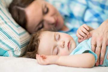 cute mother and her little son baby sleeping together in a bedroom