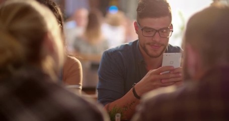 Young hipster man using mobile phone in cafe with friends - Powered by Adobe