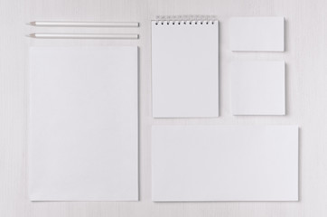 Modern blank white business stationery set with card, label, paper, notepad on soft light white wood table.