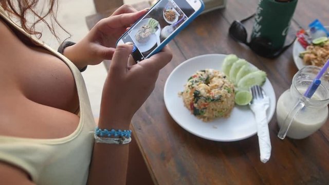 A young girl with a beautiful big chest takes a picture of her delicious dinner of rice with prawns and delicious smoothies on the phone. slow motion. 1920x1080. full hd