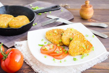 Crispy hash browns and tomatoes on a plate on a wooden table