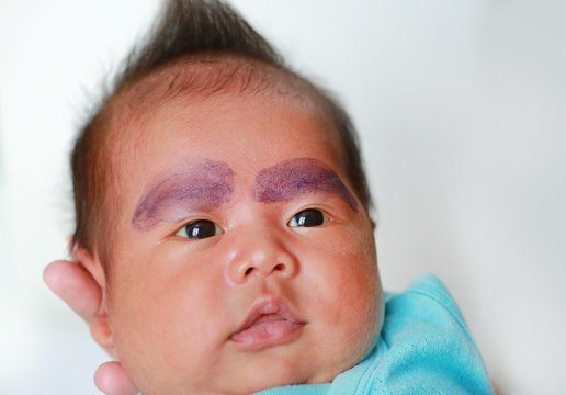 Close up face of infant baby painted eyebrows with pea flowers.