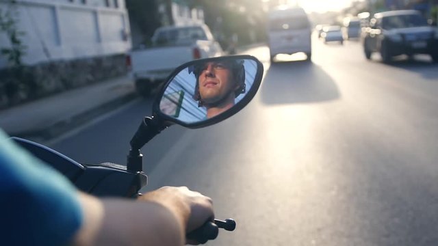 The man in the helmet will be reflected in the mirror of the motorcycle, which rides along the road lit by the sunset, the T-shirt develops in the wind. slow motion. 1920x1080. full hd