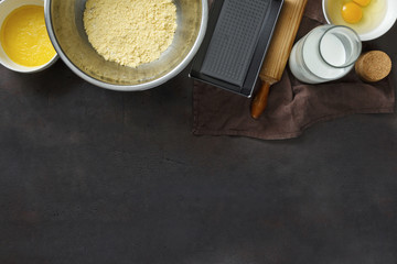 Top view raw ingredients for cooking corn bread on dark background with border
