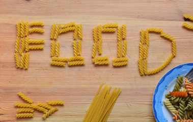The inscription FOOD made of pasta, various types of pasta whit colorful pasta served at plate/ kitchen-menu-cooking-food concept/ background 