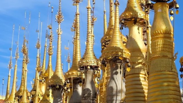 The row of golden hti decorative umbrellas with bells and wind vanes on the top of small stupas, located in site of Inn Thein Buddha image Shrine, Indein (Inn Thein) village, Inle Lake, Myanmar.