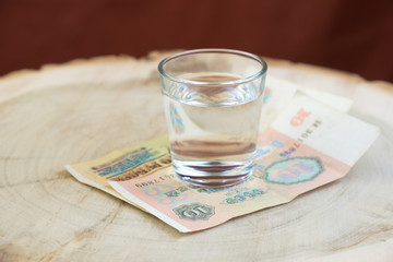 old 10 rubles ussr on the table under a glass of vodka, red background