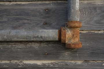 Isolated view of rusted, corroded pipe right-side placement against weathered wood backdrop