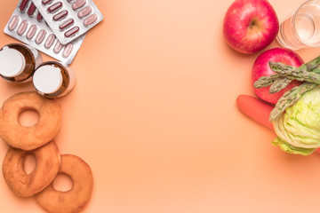 healthcare and medical concept medicine with junk bakery with the fresh vegetable and fruit on the orange background with copy space