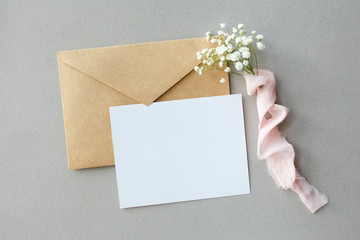 A letter on a gray background with Gypsophila with silk ribbon, invitation for a wedding, a text card and an envelope