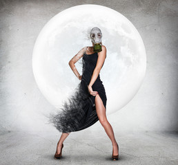 Stylish young woman in gas mask over full moon background.