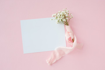 A letter on a  pink background with Gypsophila with silk ribbon, invitation for a wedding
