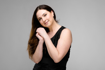 Naklejka premium Attractive young cute positive brunette caucasian smiling business woman in black dress isolated on gray