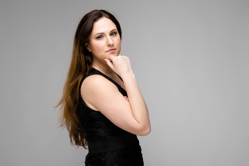 Fototapeta premium Attractive young positive brunette caucasian smiling business woman in black dress isolated on gray