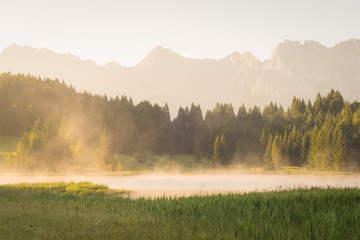 Sonnenaufgang mit Nebel über einem See in den Bergen