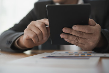 Hand of Businessman holding working digital tablet in office desk at meeting.