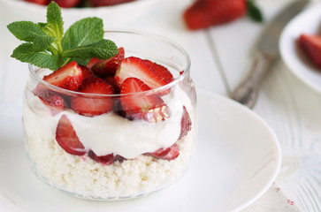 delicious and healthy breakfast cottage cheese with yogurt and fresh strawberries on white wooden background