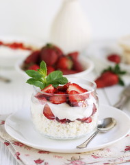 delicious and healthy breakfast cottage cheese with yogurt and fresh strawberries on white wooden background