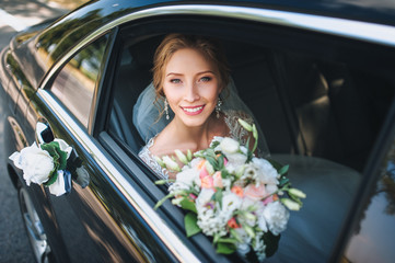 Portrait of a cute bride in a lace dress in a car window. Beautiful and smiling bride.