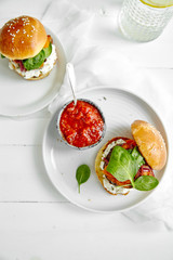 Burgers with grilled beef patties, cream cheese and spinach on classical bun. White wooden background
