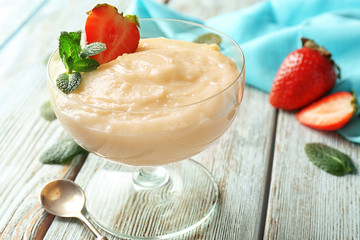 Dessert bowl with vanilla pudding and strawberry on table