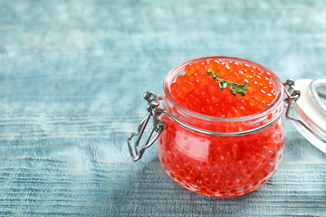 Glass jar with delicious red caviar on table