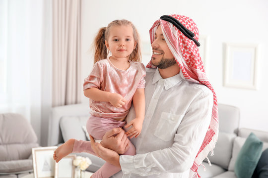 Muslim man in traditional clothes with his daughter at home