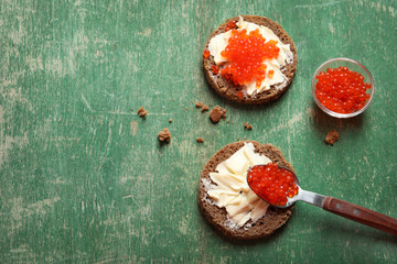 Delicious sandwiches with red caviar on wooden background, top view