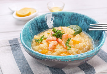 Bowl with tasty shrimps and grits on table