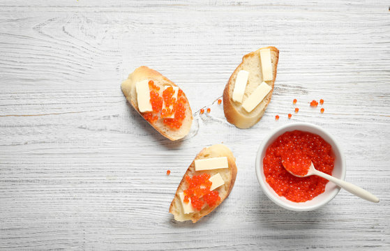 Flat lay composition with red caviar on wooden background