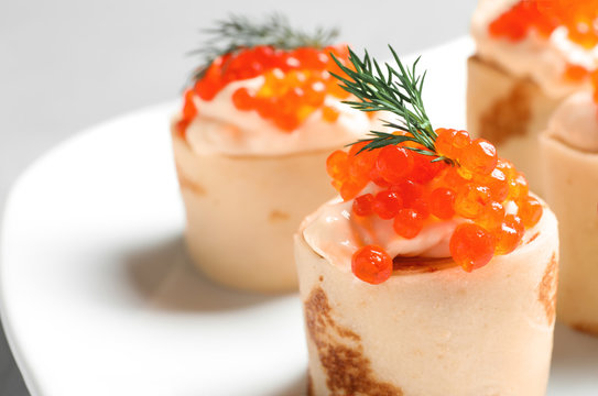 Delicious thin pancakes with red caviar, closeup