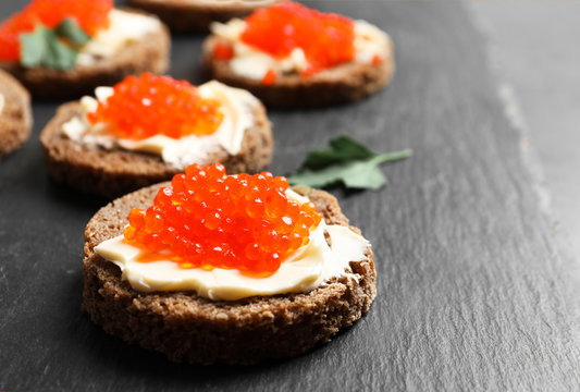 Delicious sandwiches with red caviar on slate plate