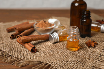 Bottles with cinnamon oil, powder and sticks on table