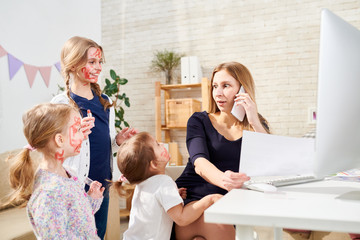 Cheerful little sisters smeared with red lipstick standing at their mother, she distracted from phone call and looking at them amazedly, interior of living room on background