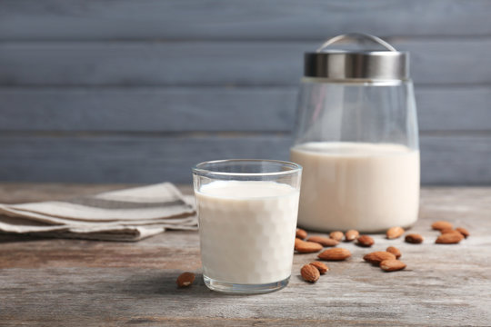 Glass with almond milk and nuts on wooden table