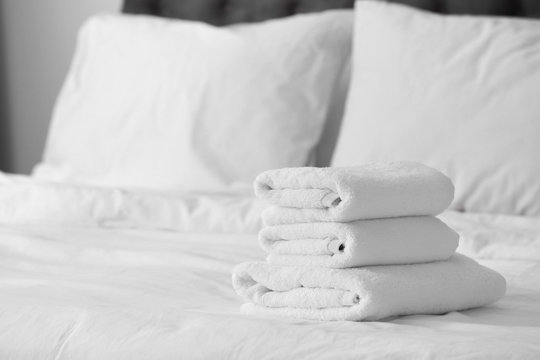 Stack of clean white towels on bed