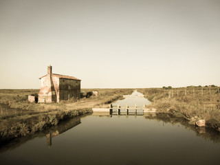 Old uninhabited house in the late afternoon long the saltmarsh in Lio Piccolo, little town near...