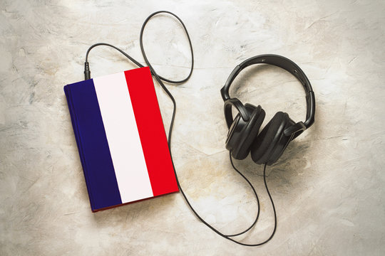 Headphones and book. The book has a cover in the form of a flag of France. Concept audiobooks. Learning languages. French language