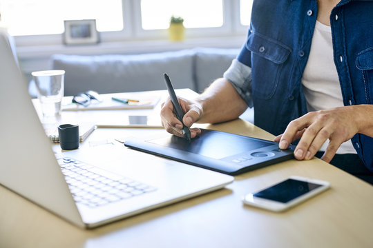 Close-up of young designer working with graphics tablet