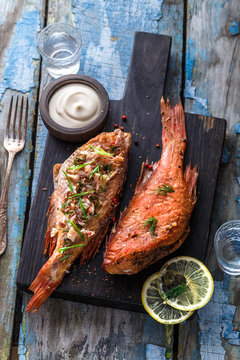 Delicious smoked fish ocean perch on wooden background, top view